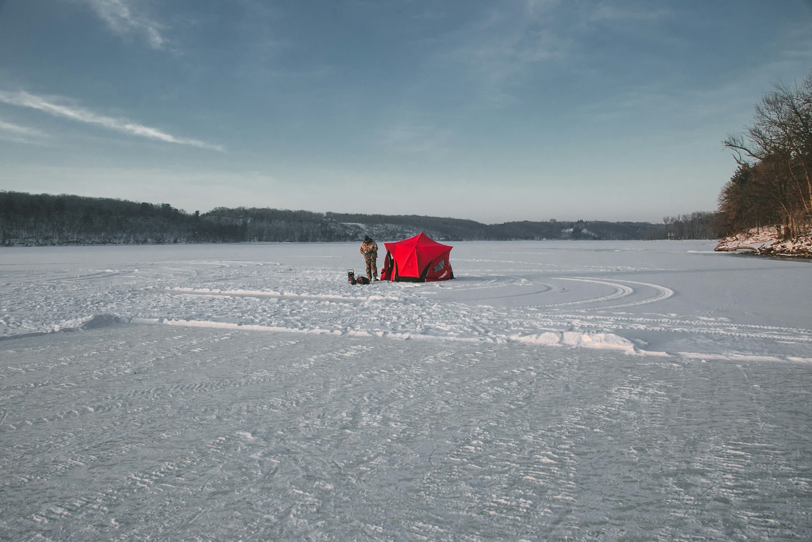 Punainen pilkkiteltta ja pilkkijä jäätyneellä järvellä
